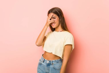 Genç sıska kadın kameraya parmaklarıyla göz kırpıyor, utanarak yüzünü kapatıyor..