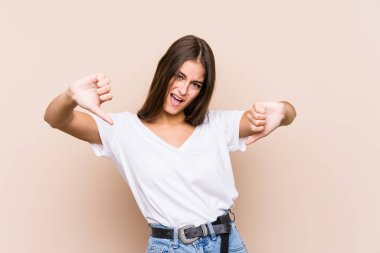 Kafkasyalı genç bir kadın soyutlanmış poz veriyor başparmağını aşağı gösteriyor ve hoşlanmadığını ifade ediyor..