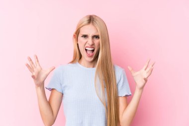 Pembe arka planda genç sarışın kadın öfkeyle bağırıyor..