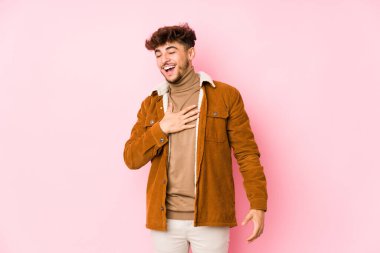 Pembe arka planda poz veren genç bir Arap.