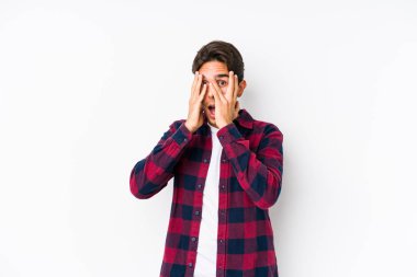 Pembe arka planda poz veren beyaz bir genç parmaklarıyla korkmuş ve gergin bir şekilde göz kırpıyor..