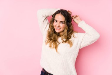 Pembe arka planda poz veren kıvrımlı genç kadın izole edilmiş kollar, rahat konum.