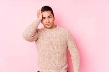 Pembe arka planda poz veren genç ve uykulu bir adam..