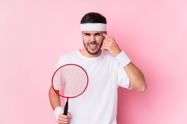 Badminton oynayan genç beyaz adam, işaret parmağıyla hayal kırıklığı jesti yapıyor..