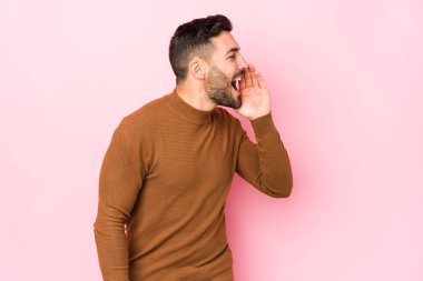 Pembe arka planda genç beyaz bir adam izole edilmiş bağırıyor ve avuç içini açık tutuyor..