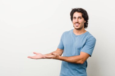 Beyaz arka planda genç ve yakışıklı bir adam avucunun içinde bir kopya alanı tutuyor..