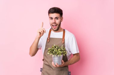 Kafkasyalı genç bahçıvan elinde bir bitki tutuyor. Bir fikri var, ilham verici bir kavram..