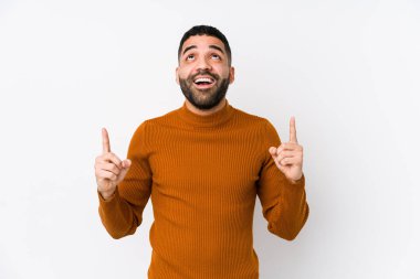 Beyaz arka planı olan genç bir latin adam, ağzı açık, üst tarafı işaret ediyor..
