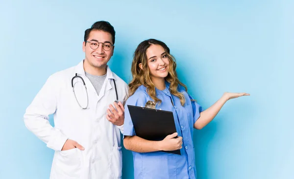 Young Doctor Couple Posing Blue Background Isolated Showing Copy Space — 스톡 사진