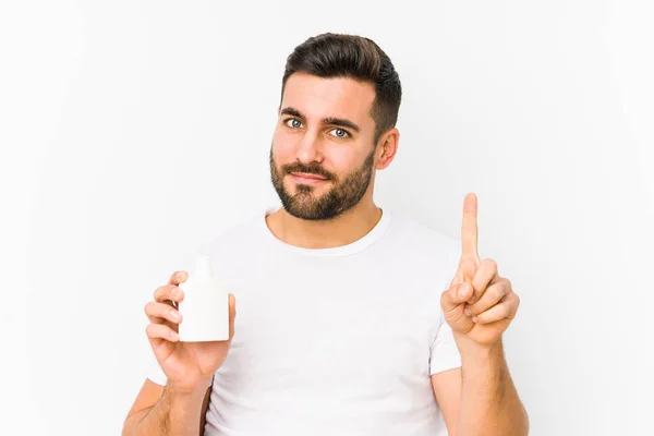 Joven Hombre Caucásico Sosteniendo Una Botella Vitaminas Aislado Mostrando Número —  Fotos de Stock