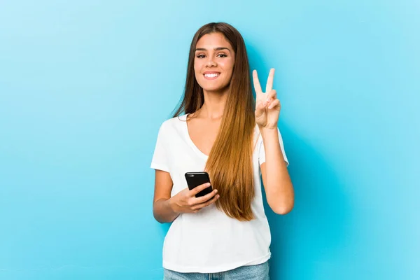 Young Caucasian Woman Holding Phone Showing Number Two Fingers — Stok fotoğraf