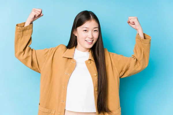 Young Chinese Woman Posing Blue Background Isolated Showing Strength Gesture — 스톡 사진