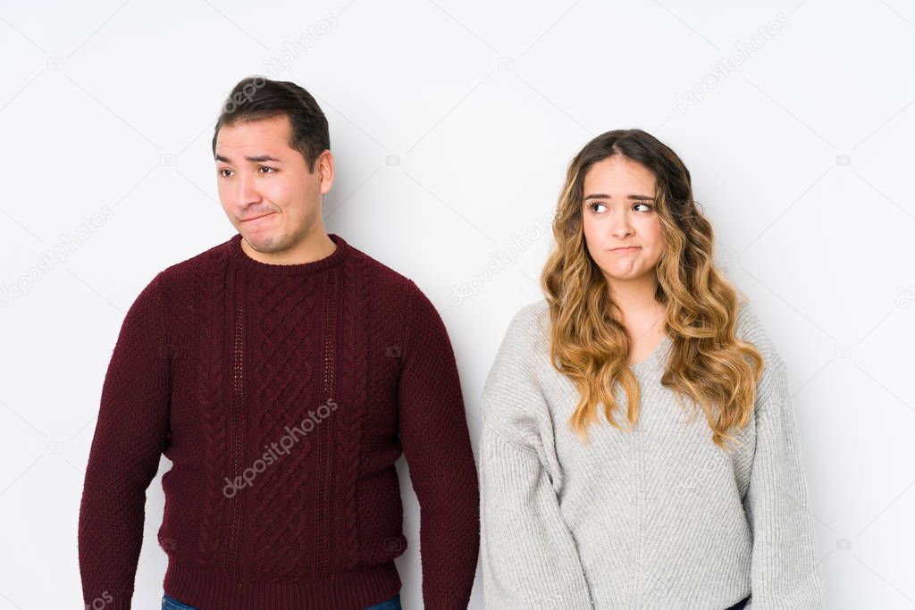 Young couple posing in a white background confused, feels doubtful and unsure.