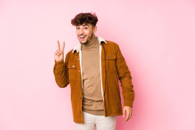 Pembe arka planda poz veren genç bir Arap.