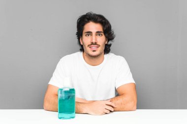 Elinde gargara tutan genç adam kollarını kavuşturarak gülümsüyor..