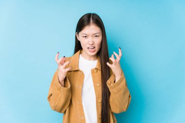 Mavi arka planda poz veren Çinli genç bir kadın gergin elleriyle bağırıyor..