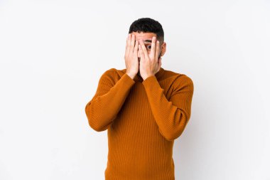 Beyaz bir geçmişi olan genç bir latin adam parmaklarının arasından korkmuş ve gergin bir şekilde göz kırpıyor..