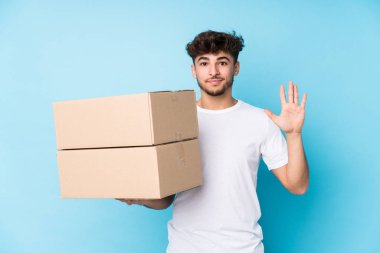 Kutuları tutan genç bir Arap beş numarayı parmaklarıyla gülümseyerek izole etti..