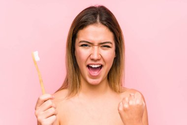 Young caucasian woman holding a teeth brush isolated cheering carefree and excited. Victory concept.