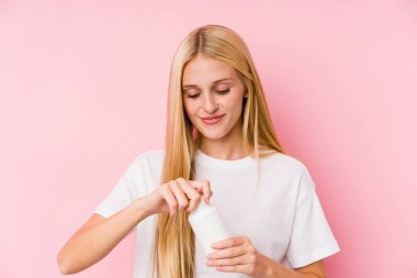 Genç sarışın bir kadın, kara zeminde izole edilmiş haplar alıyor.