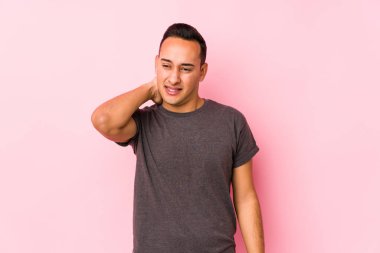 Yoong latin adam pembe arka planda poz veriyor. Oturaklı yaşam tarzından dolayı boyun ağrısı çekiyor..