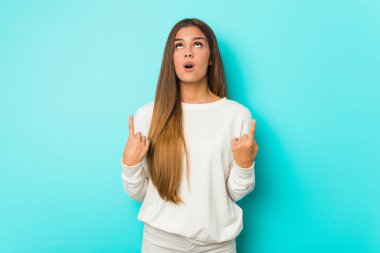 Genç, sıska bir kadın, ağzı açık, üst tarafı işaret ediyor..