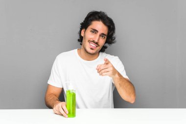 Elinde aloe vera şişesi tutan genç adam gülümsüyor..