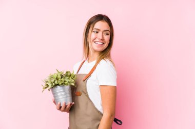 Pembe arka planda genç beyaz bahçıvan gülümseyen, neşeli ve hoş bir tarafa bakıyor..