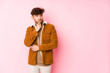 Pembe arka planda poz veren genç bir Arap.