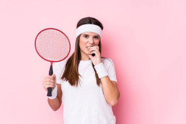 Badminton oynayan beyaz bir kadın tırnak yiyor, gergin ve endişeli..