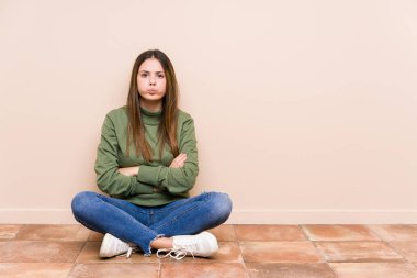 Yerde tek başına oturan beyaz bir kadın yanakları patlatıyor, yorgun bir ifade takınıyor. Yüz ifadesi kavramı.