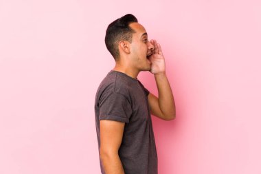 Pembe arka planda poz veren yog latin adam bağırıyor ve avuç içini açık tutuyor..