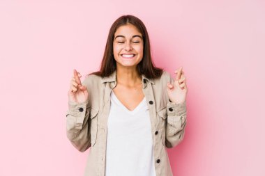 Pembe arka planda poz veren beyaz bir kadın şans getirsin diye dua ediyor.