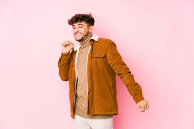 Pembe arka planda poz veren genç bir Arap.