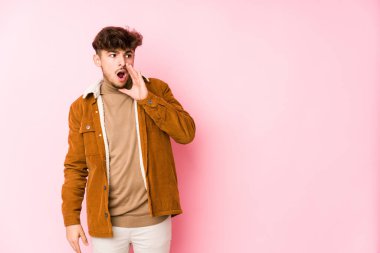 Pembe arka planda poz veren genç bir Arap.