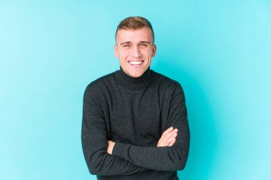 Mavi arka plandaki genç beyaz adam gülüyor ve eğleniyor..