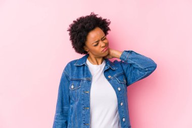 Genç Afro-Amerikalı bir kadın pembe bir sırt kaplamasına karşı sakin yaşam tarzından dolayı boyun ağrısından soyutlanmış..