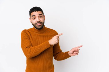 Beyaz arka planda genç bir latin adam işaret parmağıyla fotokopi alanını işaret ederek şok oldu..