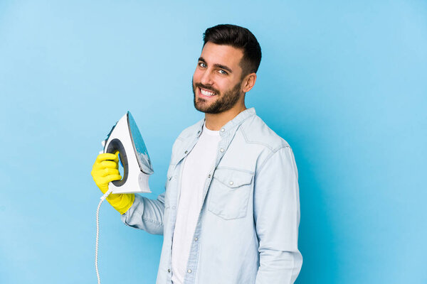 Portrait of young man ironing isolated looks aside smiling, cheerful and pleasant.