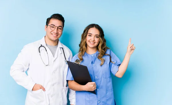 Joven Pareja Médicos Posando Fondo Azul Aislado Sonriendo Alegremente Señalando —  Fotos de Stock