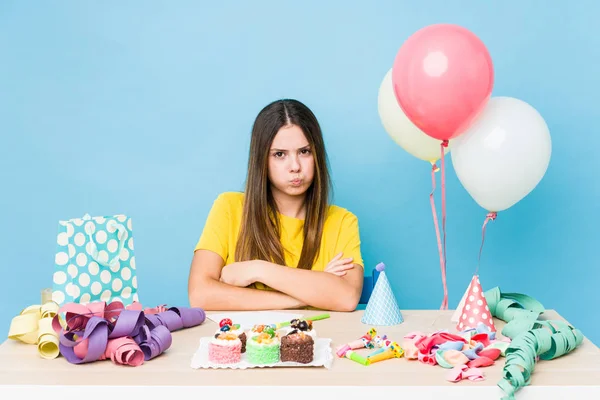 Young caucasian woman organizing a birthday blows cheeks, has tired expression. Facial expression concept.