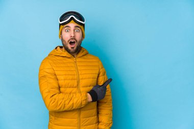 Genç kayakçı beyaz adam, yamaçtan işaret ederek izole edilmiş.