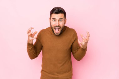 Pembe arka planda genç beyaz bir adam öfkeyle bağırıyor..