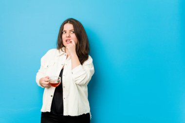 Genç kavisli kadın elinde çay fincanıyla rahatlamış fotokopi odasına bakan bir şey düşünüyor..