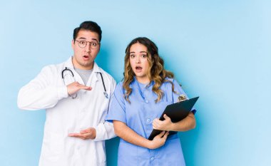Mavi arka planda poz veren genç doktor çiftin elleri arasında bir fotokopi alanı olması şaşırtıcı ve şok edici..