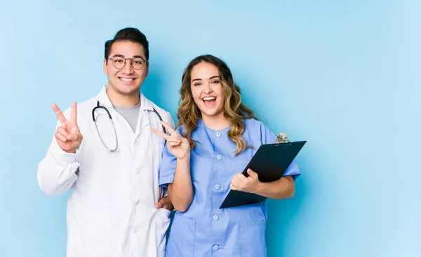 Young Doctor Couple Posing Blue Background Isolated Joyful Carefree Showing — Stock Photo, Image