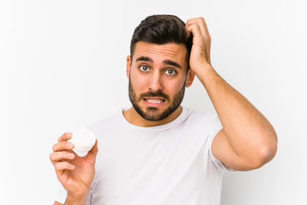 Joven Hombre Caucásico Sosteniendo Una Crema Hidratante Aislado Siendo Sorprendido —  Fotos de Stock