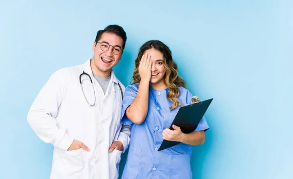 Young Doctor Couple Posing Blue Background Isolated Having Fun Covering — 스톡 사진