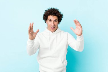 Mavi arka planda genç sporcu hoş bir sürprizle karşılaşıyor, heyecanlı ve el kaldırıyor..