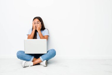 Dizüstü bilgisayarda çalışan genç Hintli kadın korkmuş ve gergin parmaklarıyla gözünü kırp..